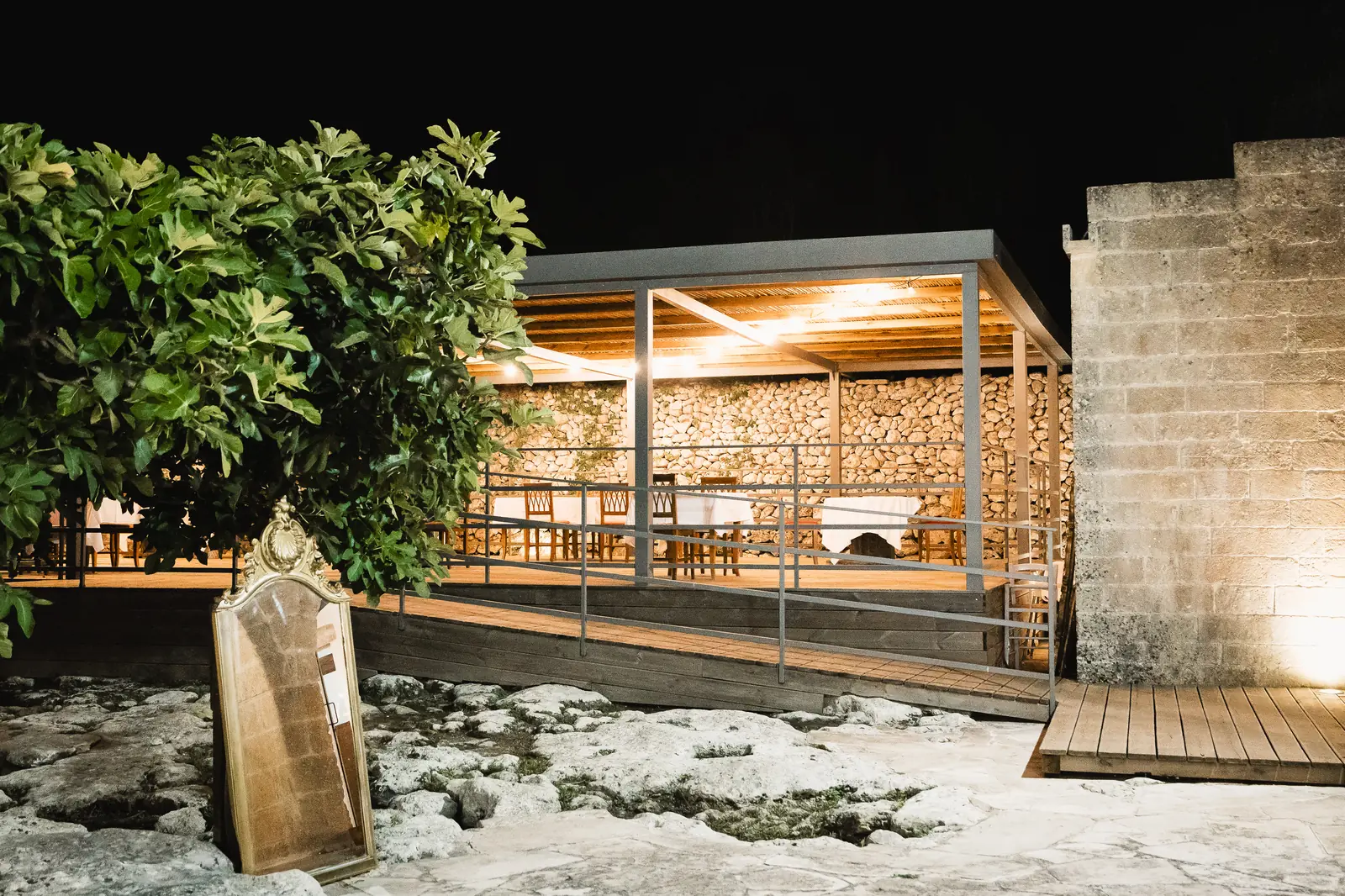 La loggia della masseria illuminata la sera, apparecchiata per un evento privato nel Salento